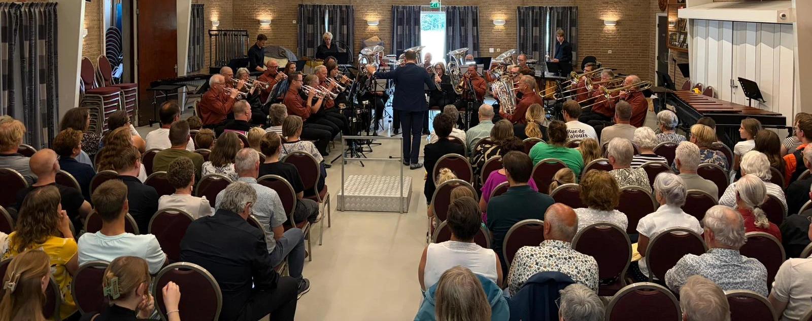 Brassband Apeldoorn met dirigent en publiek tijdens een concert